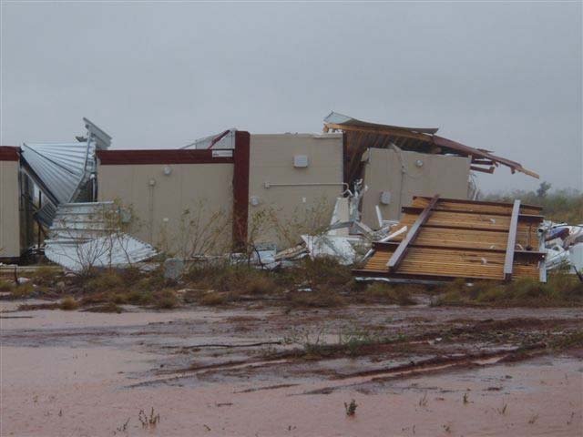 Close-up photo of ripped metal and broken buildings at a mine camp
